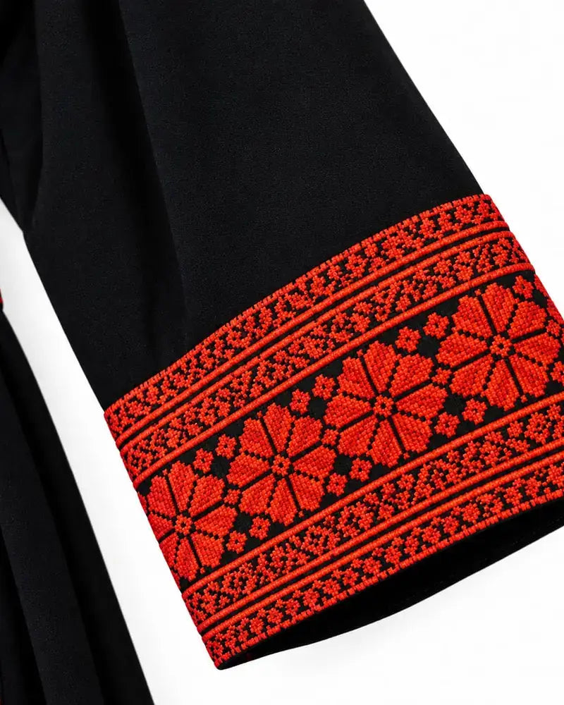 Traditional Palestinian thobe with red embroidery showcasing intricate red embroidery on black fabric.